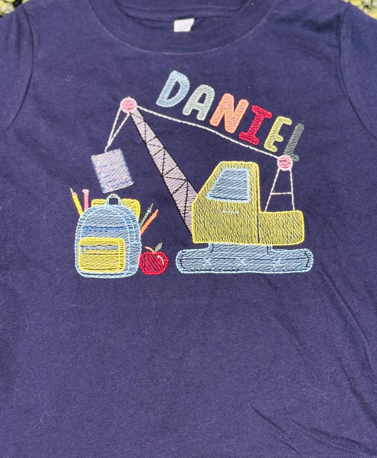 Purple children’s shirt personalized for Daniel with construction vehicle embroidery