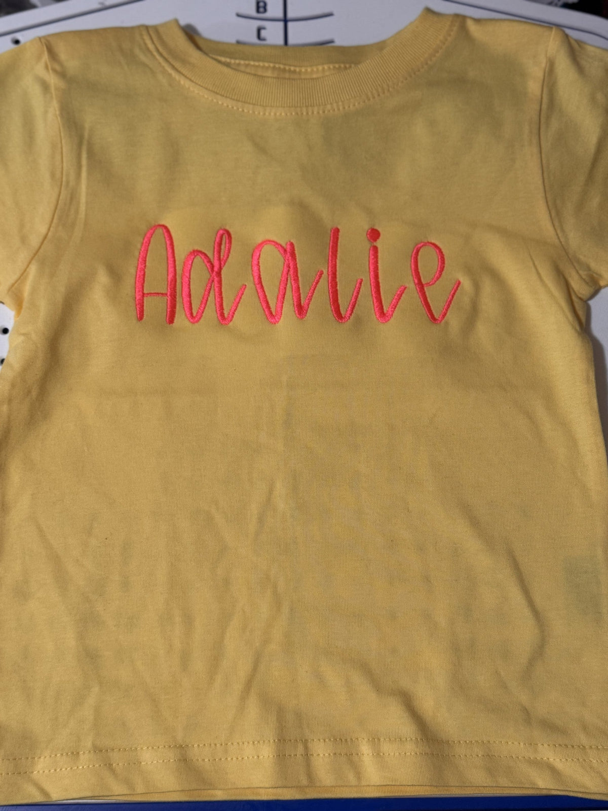 Mustard T-shirt embroidered with the personalized script name Adalie