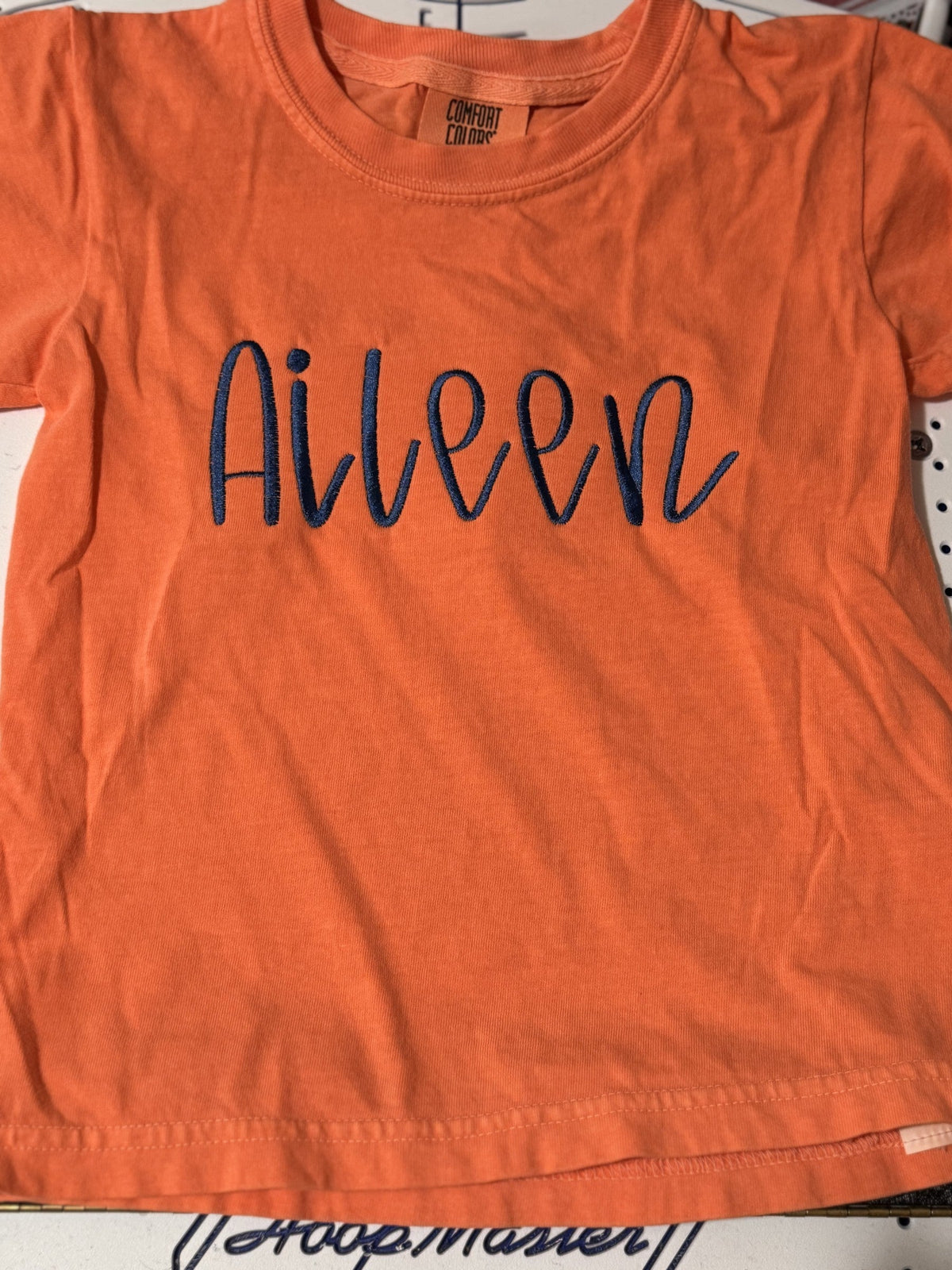 Orange T-shirt embroidered with the personalized script name Ailveen