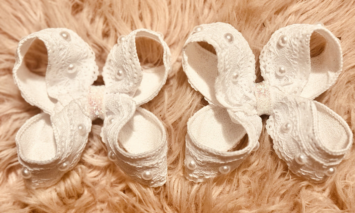 Set of white embroidered handmade bows on a soft neutral background