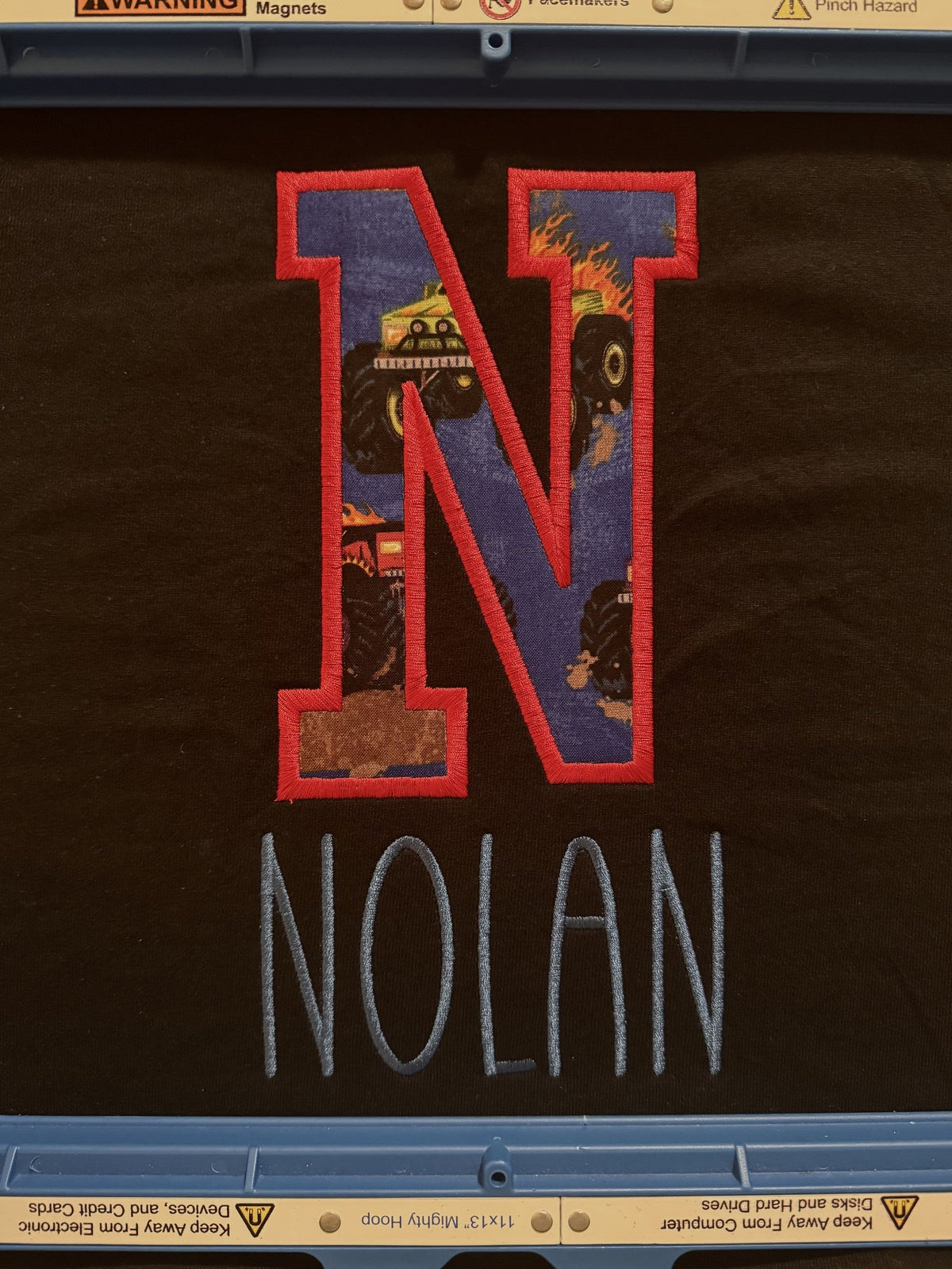 Dark fabric personalized with a large applique letter N and the name Nolan