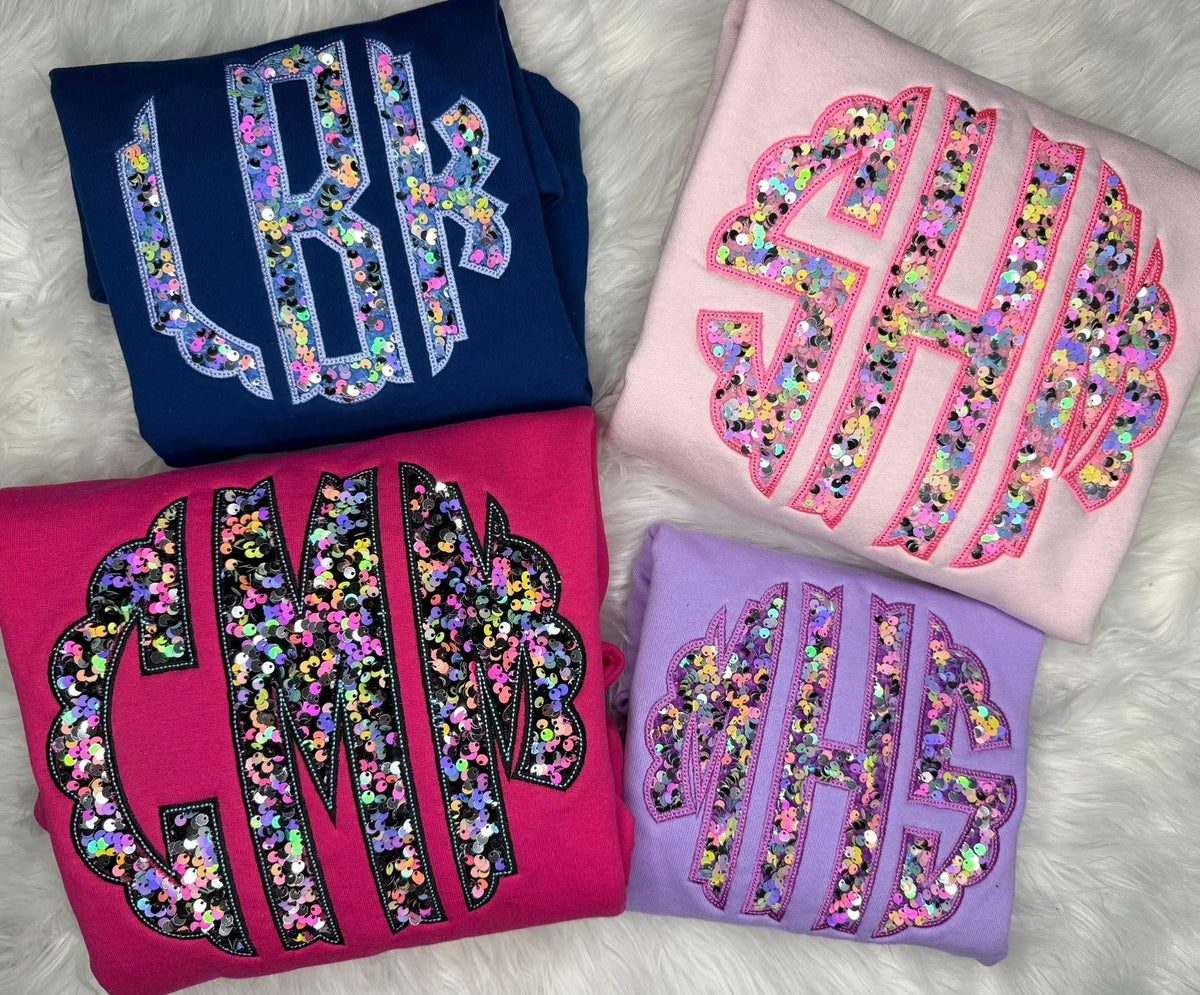Four folded shirts showing colorful patterned three-letter monogram applique styles
