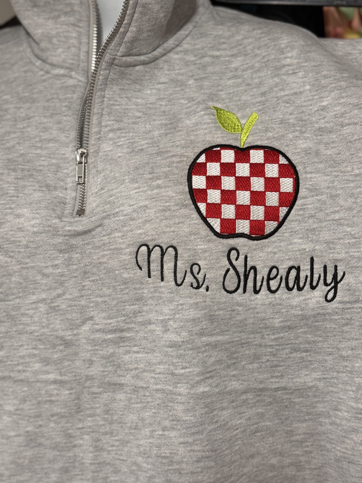 Gray quarter-zip embroidered for Mrs. Sheally with a teacher apple design