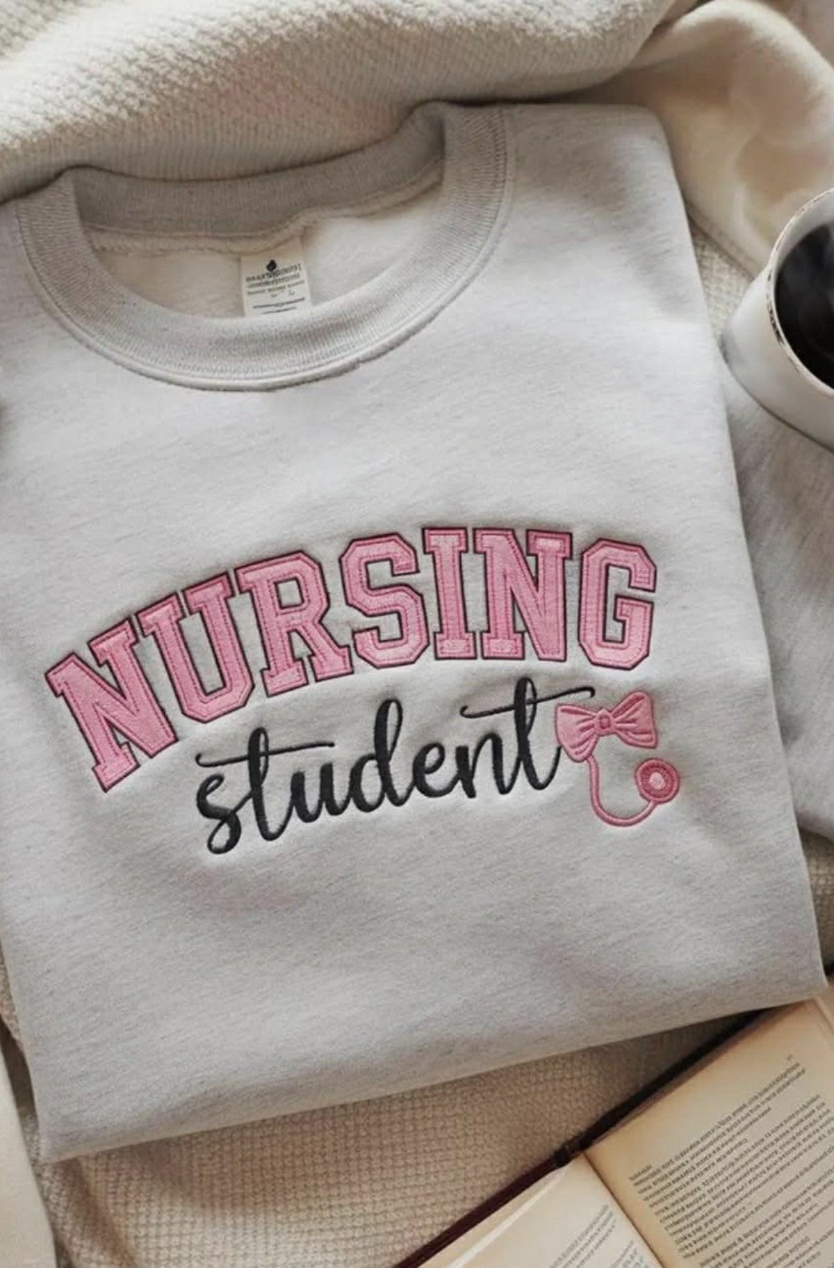 White sweatshirt embroidered with colorful Nursing Student lettering