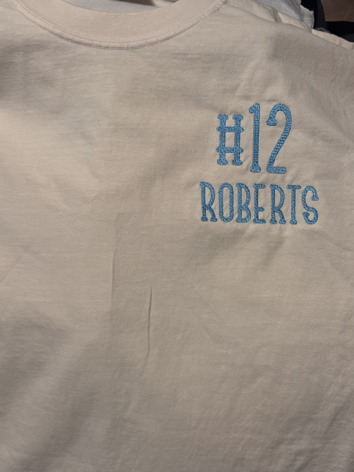 White sports shirt embroidered with player number 12 and the name Roberts