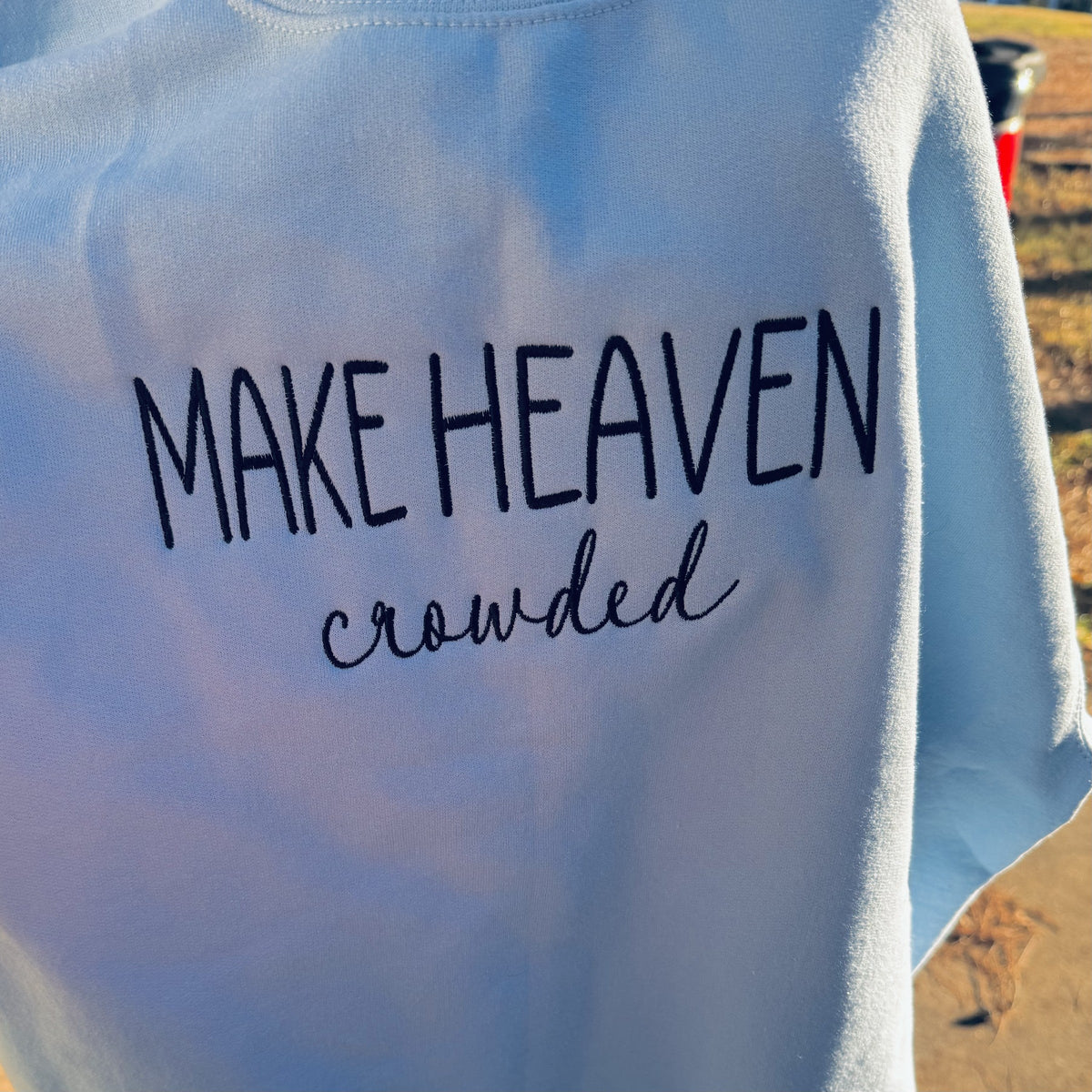 Blue sweatshirt embroidered with the phrase Make Heaven Crowded