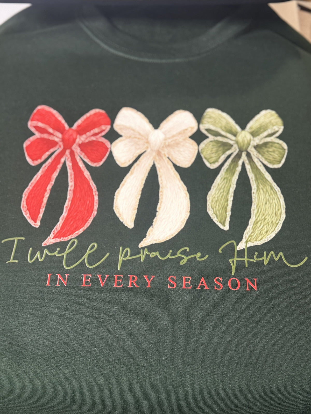 Dark green sweatshirt with three holiday bow appliques and faith-inspired seasonal text