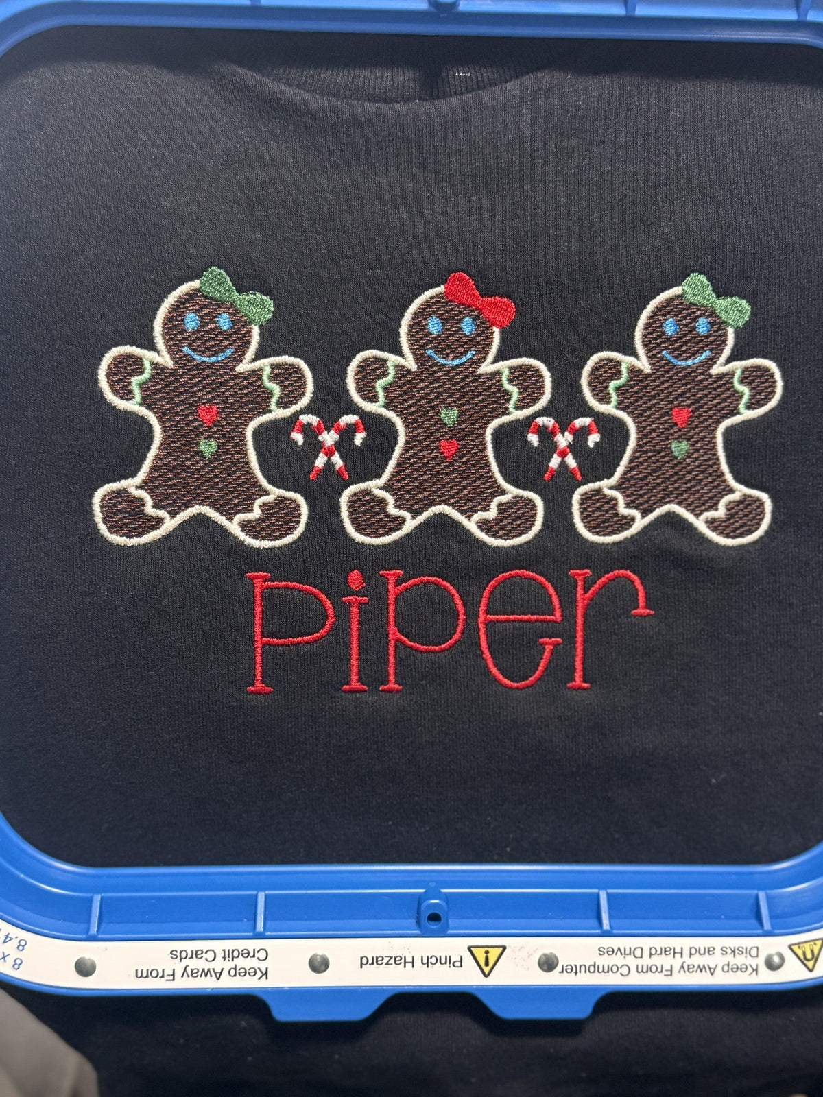 Gingerbread family embroidery personalized for Piper shown in an embroidery hoop