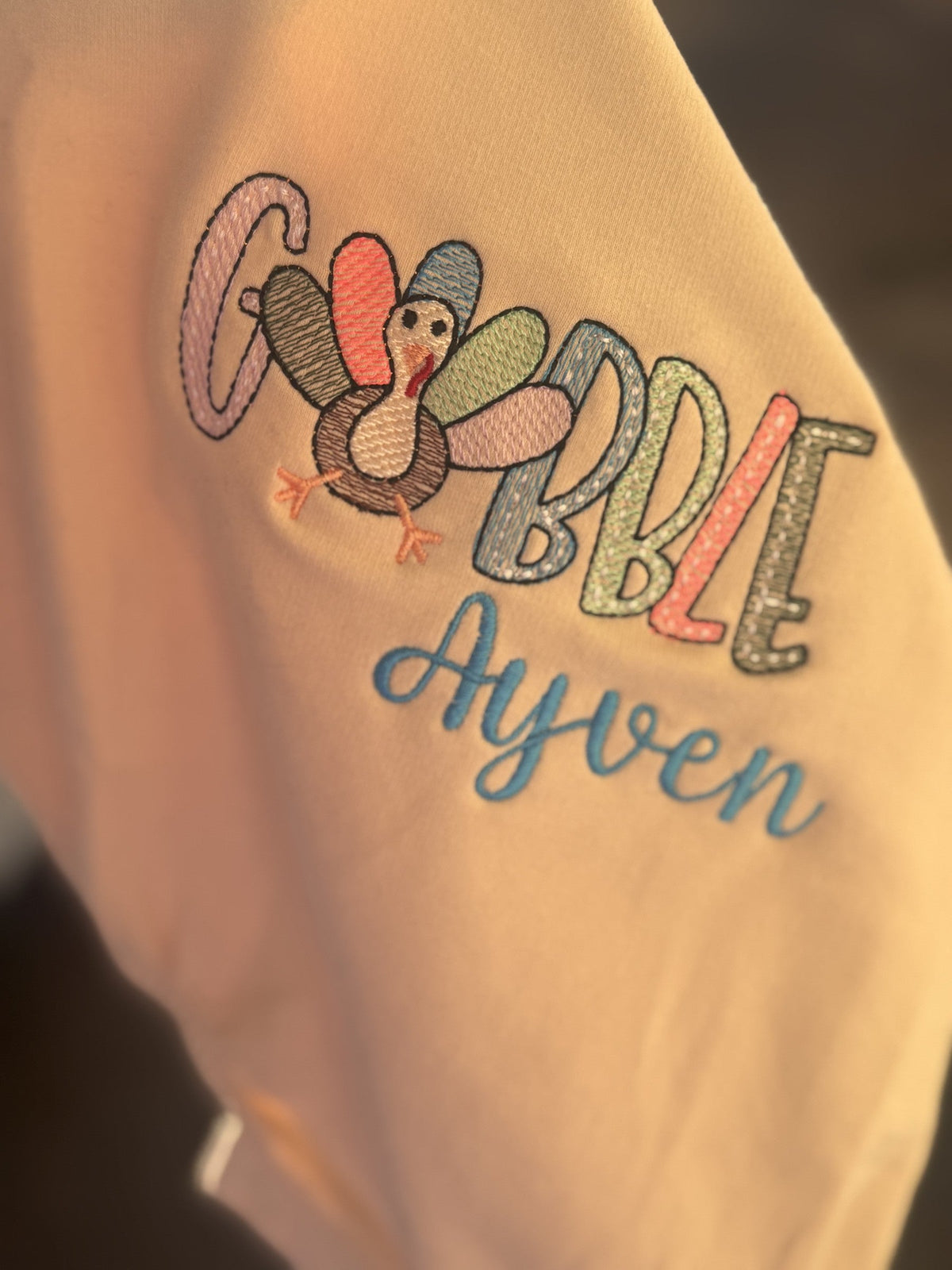 Tan shirt personalized for Ayven with colorful Thanksgiving Gobble turkey embroidery