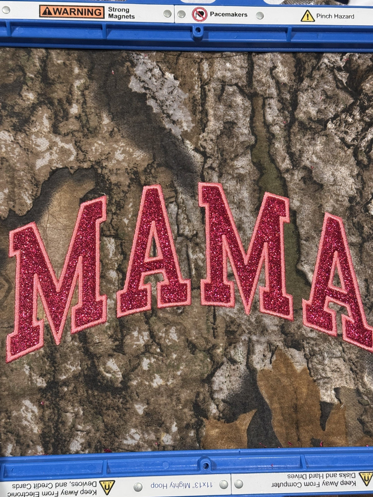 MAMA applique embroidery in pink patterned letters shown in an embroidery hoop