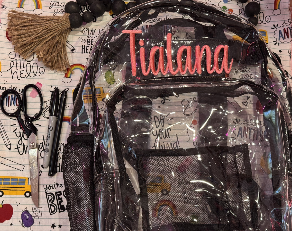 Clear backpack personalized with the name Indiana in coral embroidery