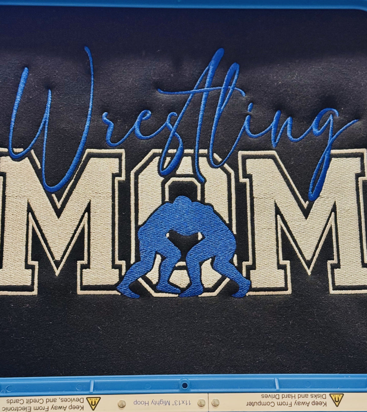 Dark fabric with blue and white Wrestling Mom applique embroidery