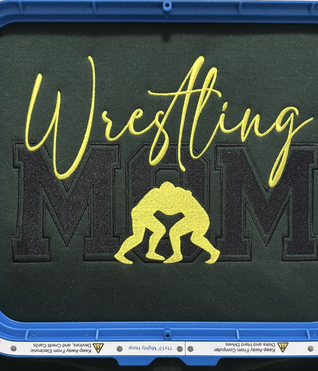 Dark fabric with Wrestling Mom design shown in an embroidery hoop