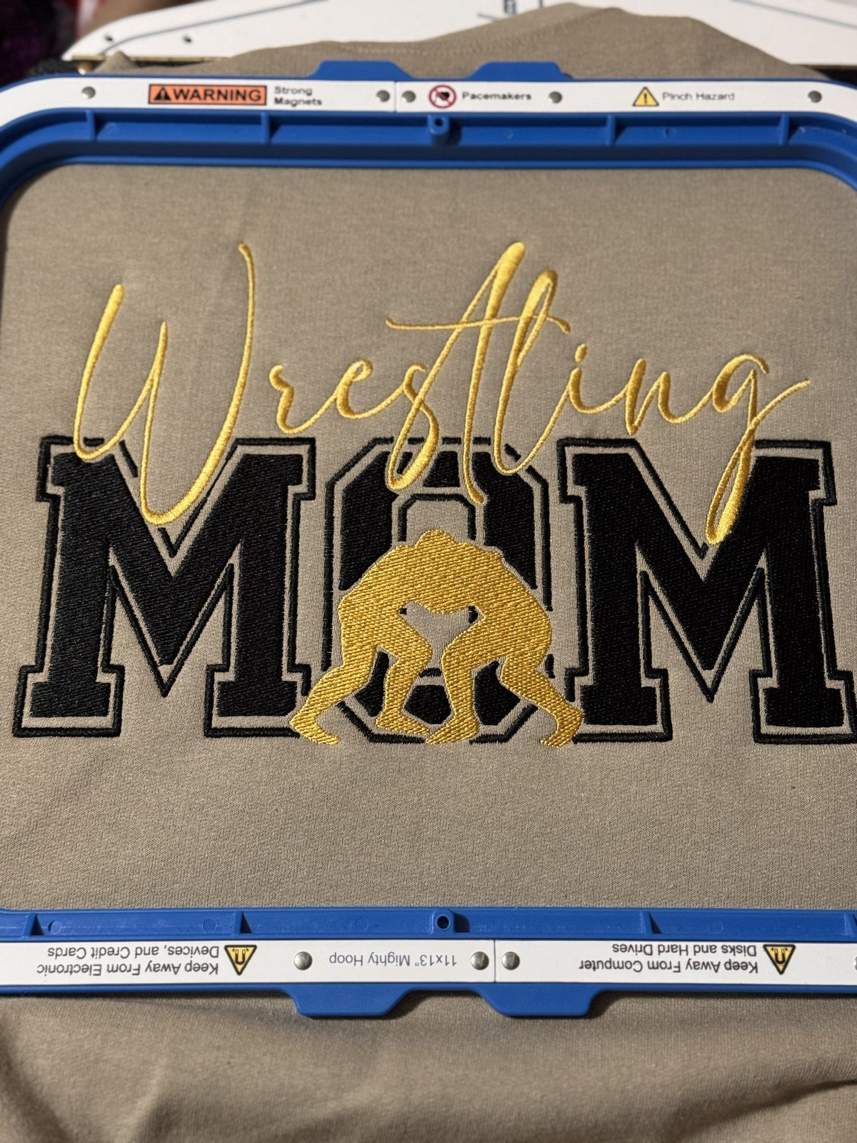 Tan fabric with black and gold Wrestling Mom applique embroidery